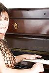 di età maturo donna signora Sarah giocare pianoforte in vedere al maglia vestito